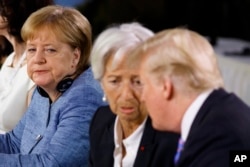 FilE - German Chancellor Angela Merkel watches as President Donald Trump talks with IMF Managing Director Christine Lagarde during the Gender Equality Advisory Council breakfast during the G-7 summit, June 9, 2018, in Charlevoix, Canada.