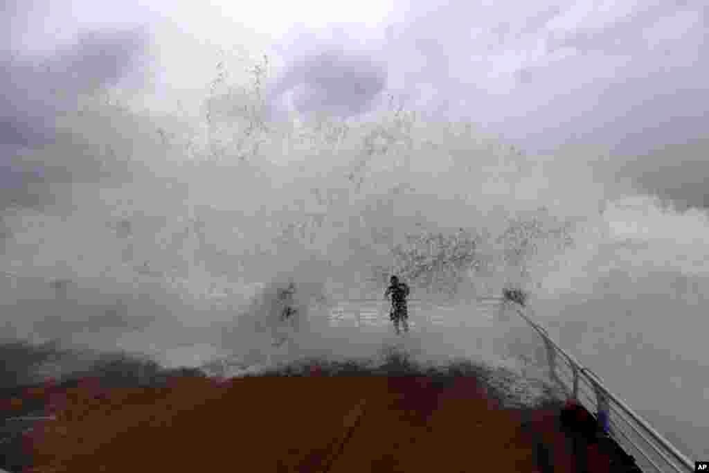 Waves crash over people on the seafront at the Corniche, or waterfront promenade, in Beirut, Lebanon. 