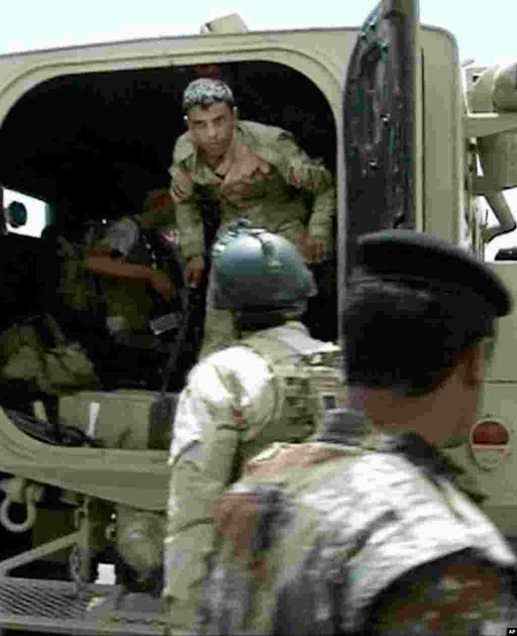 This image taken from video obtained from the Iraqi Military shows an armed Iraqi soldier leaving a military vehicle during clashes in the northern city of Mosul, Iraq, June 9, 2014.