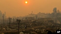 A couple walks through a neighborhood destroyed by wildfires in Chile's Santa Olga community, Jan. 26, 2017. Officials say the town was consumed by the country's worst wildfires.