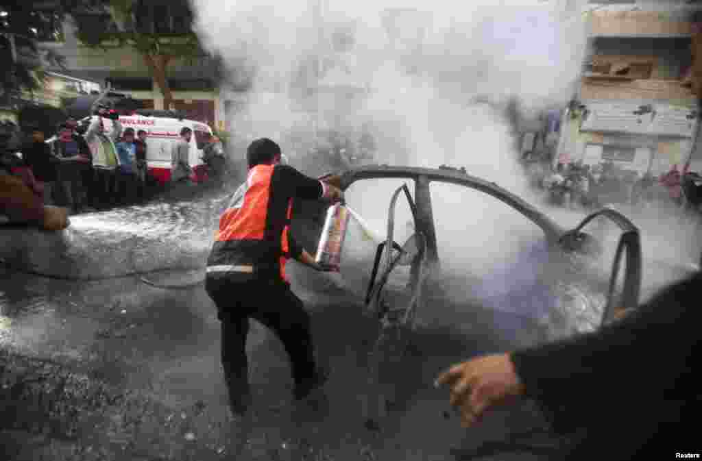 Palestinians extinguish a fire after an Israeli air strike on a car carrying Hamas military chief Ahmed al-Jaabari, Gaza City November 14, 2012.