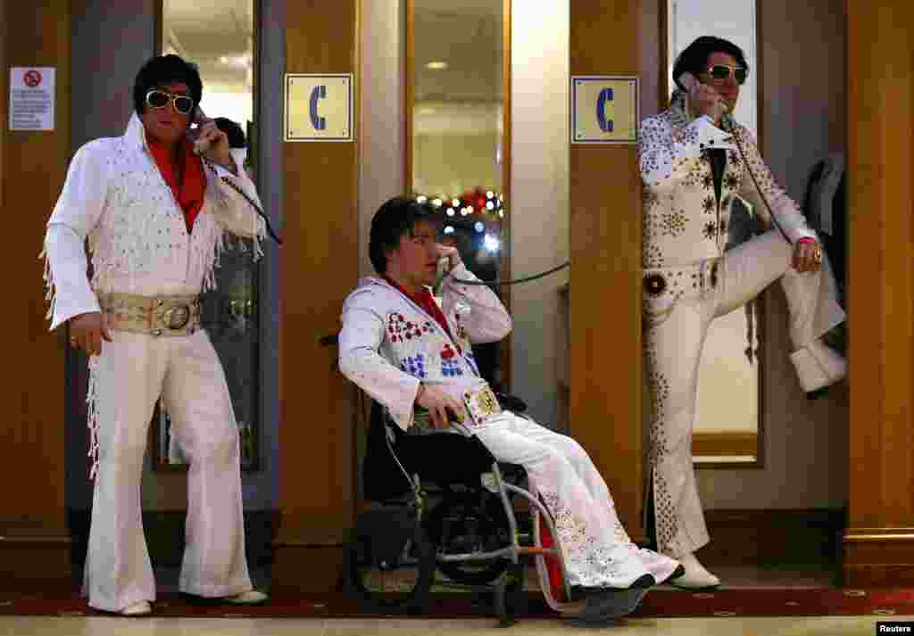 Para kontestan amatir (dari kiri) Phil Bailey, John Hindle, dan Emir Eren berpose di bilik-bilik telepon dalam acara tahunan Kontes dan Konvensi Tribut untuk Artis Elvis se-Eropa di Birmingham, Inggris. &nbsp;