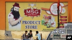 People sit outside a store belonging to Dera Sacha Sauda sect leader Gurmeet Ram Rahim Singh after it was closed down by authorities near Sonipat, India, Aug. 26, 2017. 