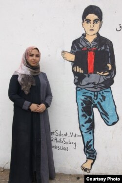 Yemeni artist Haifa Subay stands in front of one of her murals in the Yemeni capital, Sanaa. The mural shows a boy holding a leg he lost in a land mine explosion — one of the issues Subay wants to shed light on.