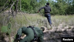 Seorang pria yang menerobos perbatasan AS dari wilayah Meksiko, tampak berlari menghindari kejaran petugas patroli perbatasan AS di kota McAllen, Texas, 8 Mei 2018. 