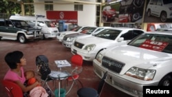 A potential customer breastfeeds her baby a saloon for newly imported cars in Rangoon.