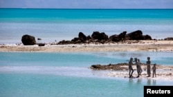 Trẻ em trên đảo South Tarawa, nước Cộng hòa Kiribati. Quốc gia này gồm 33 đảo san hô chỉ cao hơn mực nước biển 1 mét. Với tình trạng mực nước biển dâng lên, Tổng thống nước này tiên đoán nước ông sẽ không còn người ở trong 30 đến 60 năm vì nước ngập và ô nhiễm nguồn cung cấp nước ngọt