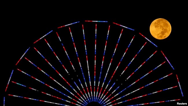 FILE - The moon is pictured behind a Ferris wheel on the pier in Santa Monica, California, after a total lunar eclipse, also known as a