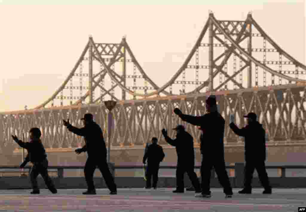 Chinese people perform a morning exercise with a backdrop of Friendship Bridge linking between China and North Korea, in Dandong, China, Friday, Nov. 26, 2010. Chinese Premier Wen Jiabao responded by calling on all sides to show "maximum restraint" and pu