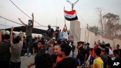 Protesters raise the Iraqi flag at the gate of the Iranian consulate building before storming and burning it in Basra, 340 miles (550 km) southeast of Baghdad, Iraq, Sept. 7, 2018. 