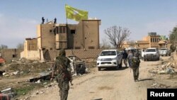 FILE - A Syrian Democratic Forces flag flutters on a damaged building in the town of Baghuz, Syria, March 23, 2019. 