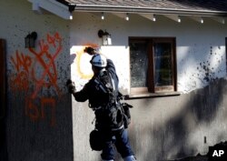 A member of a search and rescue crew marks a home as searched, Jan. 13, 2018, in Montecito, Calif.