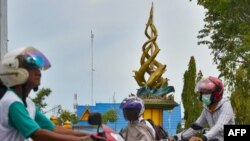 Pengendara motor melintas di depan Tugu Antikorupsi di Pekanbaru, Riau, 9 November 2017. (Foto: AFP)