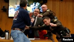 Randall Margraves, left, lunges at Larry Nassar (wearing orange) a former team USA Gymnastics doctor who pleaded guilty in November 2017 to sexual assault charges, during victim statements of his sentencing in the Eaton County Circuit Court in Charlotte, Michigan, Feb. 2, 2018.