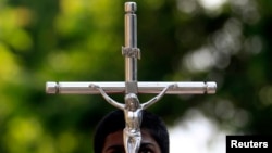 An altar boy looks up at a crucifix he is holding during a special Good Friday mass at a church in Colombo, April 18, 2014.