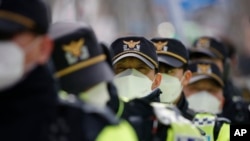 戴口罩的韩国警察在首尔的一个集会上维持秩序 （2月22日）