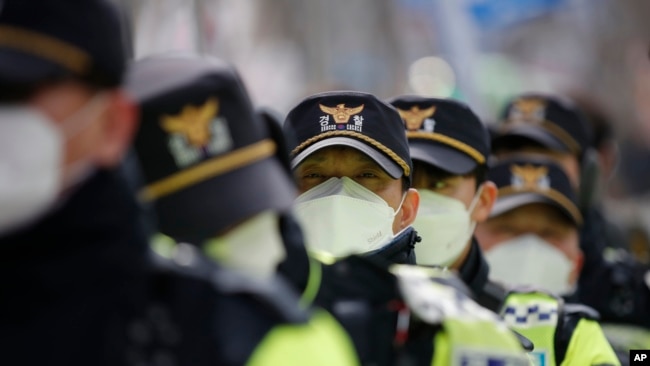 戴口罩的韩国警察在首尔的一个集会上维持秩序 （2月22日）
