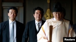Japan's Prime Minister Shinzo Abe (C) is led by a Shinto priest as he visits Yasukuni shrine in Tokyo, Dec. 26, 2013.