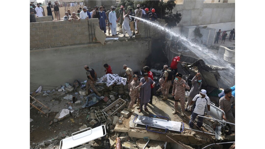 Tentara dan sukarelawan mengumpullkan jenazah korban di lokasi jatuhnya pesawat di Karachi, Pakistan, 22 Maret 2020.