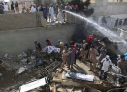 Tentara dan sukarelawan mengumpullkan jenazah korban di lokasi jatuhnya pesawat di Karachi, Pakistan, 22 Maret 2020.