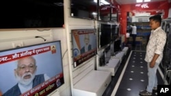 A salesman watches Indian prime minister Narendra Modi addressing the nation on a television in Mumbai, India, Wednesday, March 27, 2019. (AP Photo/Rajanish Kakade)