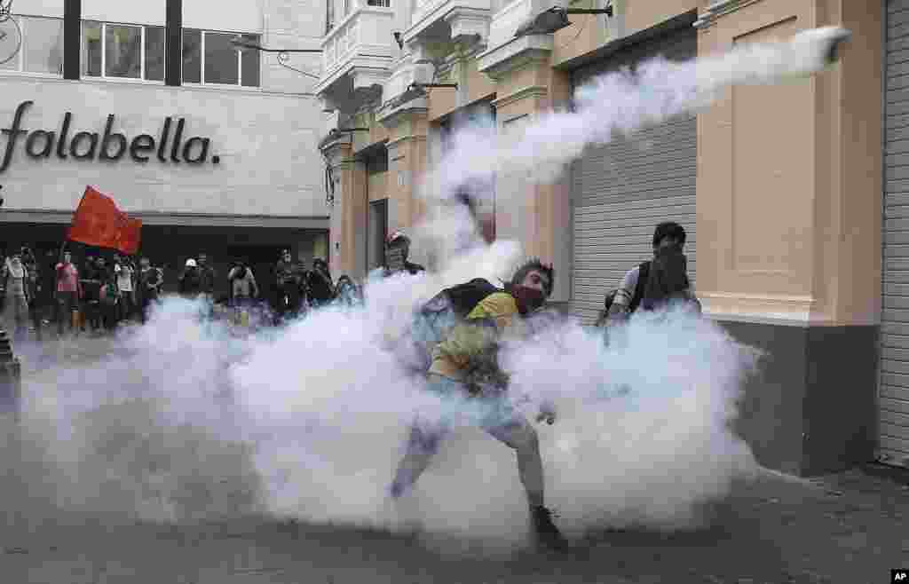 A demonstrators throws a tear gas canister back towards the police during clashes against the pardon of former President Alberto Fujimori in Lima, Peru, Dec. 25, 2017. President Pedro Pablo Kuczynski announced Sunday night that he granted a medical pardon to the jailed former strongman who was serving a 25-year sentence for human rights abuses, corruption and the sanctioning of death squads.