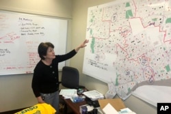 In this Nov. 22, 2019, photo, Detroit 2020 Census Campaign executive director Victoria Kovari looks over a Detroit map showing city neighborhoods that were under-counted in the 2010 census. (AP Photo/Corey Williams)