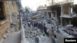 People inspect the damage at a site after it was hit by shelling carried out by rebels at Syrian government-held areas of Aleppo, Syria, in this handout picture provided by SANA on July 11, 2016.