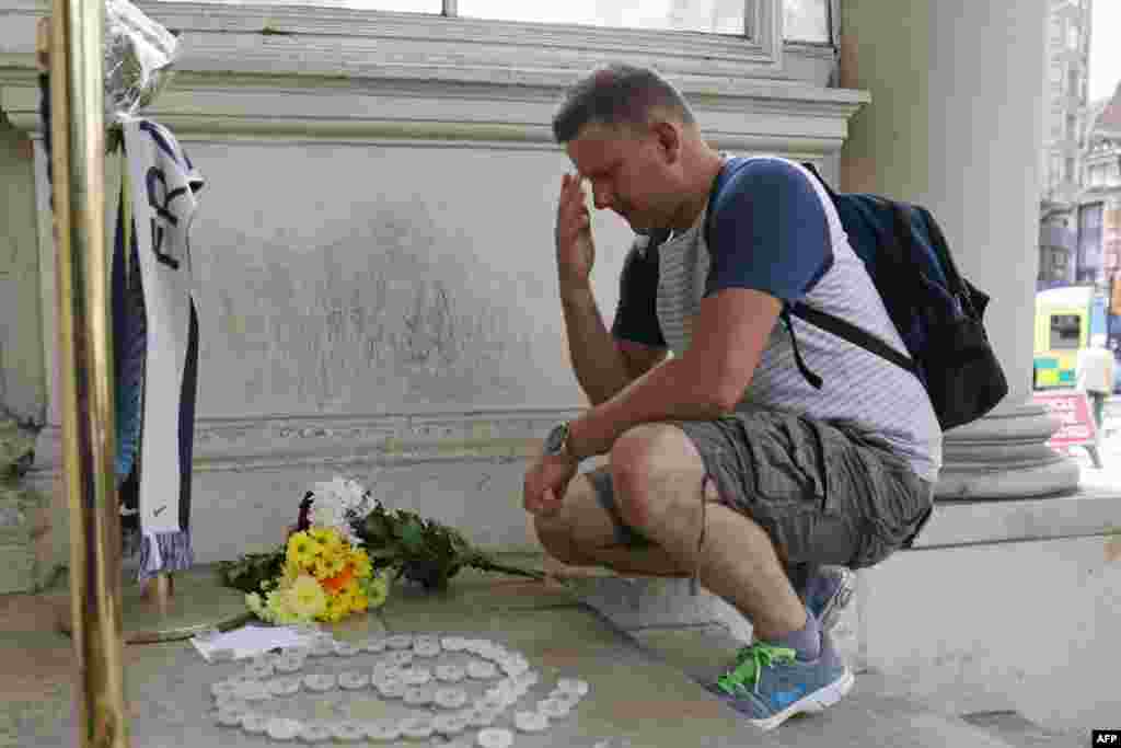 A man pauses while he leaves a bunch of flowers outside the French embassy in London on July 15, 2016 in solidarity following the attack in the southern French city of Nice. 