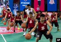 NBA star Jeremy Lin helps a young player during a basketball camp in Beijing, China, Aug. 25, 2013.