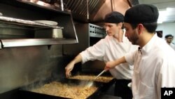 Sous chefs Adan Franco, right, and Casey Davison of the Sanford Restaurant season and stir cassoulet, to be delivered to the Guest House homeless shelter in Milwaukee, Dec. 8, 2015.