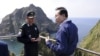 South Korean President Lee Myung-bak, right, talks with police officer Yoon Jang-soo as Lee visits islands called Dokdo in Korea and Takeshima in Japan, Aug. 10, 2012.