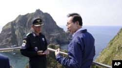 South Korean President Lee Myung-bak, right, talks with police officer Yoon Jang-soo as Lee visits islands called Dokdo in Korea and Takeshima in Japan, August 10, 2012.