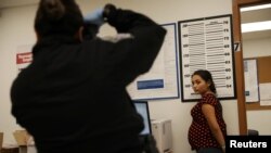 A pregnant woman who is seeking asylum has her picture taken by a U.S. Customs and Border patrol officer at a pedestrian port of entry from Mexico to the United States, in McAllen, Texas, May 10, 2017.