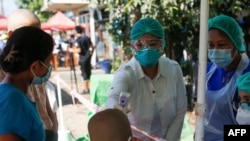 ရန်ကုန်မြို့ရှိ လမ်းတခုမှာ ကိုယ်အပူချိန်တိုင်းပေးနေတဲ့ ကျန်းမာရေးဝန်ထမ်းတချို့ (မေ ၁၆၊ ၂၀၂၀)