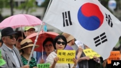 South Koreans hold signs and a national flag during a rally to support a plan to deploy an advanced U.S. missile defense system called Terminal High-Altitude Area Defense, or THAAD, in Seoul, South Korea, July 18, 2016.