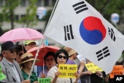 South Koreans hold signs and a national flag during a rally to support a plan to deploy an advanced U.S. missile defense system called Terminal High-Altitude Area Defense, or THAAD, in Seoul, South Korea, July 18, 2016.