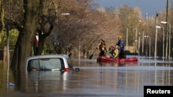 Rescue workers remove local residents by boat from a flooded residential street in Carlisle, Britain December 6, 2015.