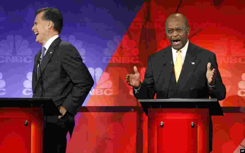 Republican presidential candidates former Massachusetts Governor Mitt Romney (L) reacts as businessman Herman Cain speaks at the CNBC Republican presidential debate in Rochester, Michigan, November 9, 2011. REUTERS/Mark Blinch (UNITED STATES - Tags: POL