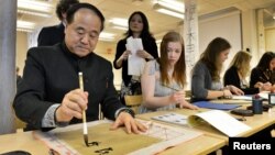 Mo Yan, Chinese winner of the 2012 Nobel Prize in Literature, demonstrates Chinese calligraphy to a student during a visit to a high school in Lidingo, outside Stockholm, Dec. 7, 2012. 