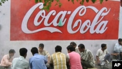 FILE - A way side vendor serves breakfast to customers beneath an advertisement for Coca Cola in New Delhi, India, May 23, 2007. Traders in the southern state of Tamil Nadu, angry at U.S.-based animal rights group PETA over its role in a bull-taming ban, have turned their ire on iconic U.S. brands Coke and Pepsi.