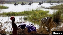 Nigerians fleeing Boko Haram attacks continue to enter Chad; men on camels cross the water as a woman washes clothes in Lake Chad at Ngouboua, Jan. 19, 2015.