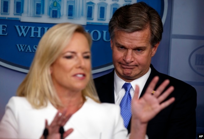 FBI Director Christopher Wray listens as Secretary of Homeland Security Kirstjen Nielsen speaks during the daily press briefing at the White House, Aug. 2, 2018, in Washington.