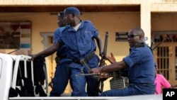 FILE - Police drive by the scene of a grenade attack on a parked car downtown Bujumbura, Burundi, on the eve of a presidential election, July 20, 2015.