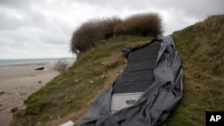 FILE: A damaged inflatable small boat is pictured on the shore in Wimereux, northern France, Thursday, 11.25.2021 in Calais, France across the English Channel from Britain
