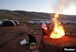 FILE - Yazidi women prepare bread at a refugee camp in Mount Sinjar, Iraq, Feb. 4, 2019.