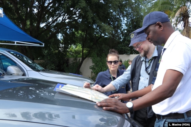 Members of the EU observer mission team look at an electoral map to identify areas where they will be deployed.