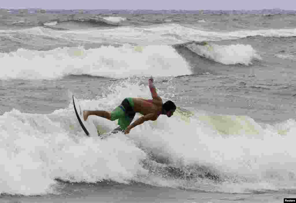 A surfer takes advantage of higher waves as winds from Hurricane Sandy began to affect weather in Boca Raton, Florida, October 25, 2012.