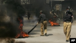 A Pakistani police officer tires set alight by protesters to condemn the killings of Shiite Muslims in Quetta, Pakistan, October 4, 2011.