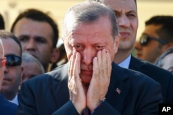 Turkish President Recep Tayyip Erdogan right, wipes his tears during the funeral of Mustafa Cambaz, Erol and Abdullah Olcak, killed Friday while protesting the attempted coup against Turkey's government, in Istanbul, July 17, 2016.